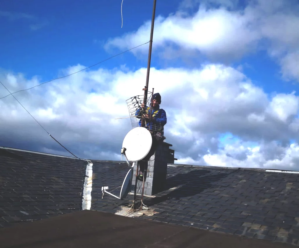 Trabajador realizando instalación de una antena parabólica